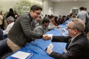 Two people shake hands at a speed networking and recruitment event